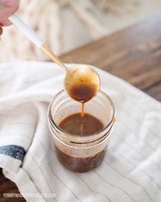 a person holding a spoon full of chocolate sauce on top of a white dish towel