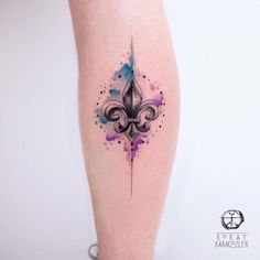 a woman's leg with a watercolor fleur de lis tattoo on it