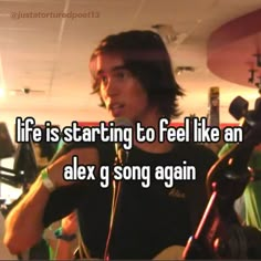 a man holding a guitar in his right hand with the words life is starting to feel like an alex g song again