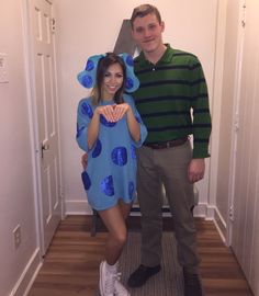 a man standing next to a woman in a blue monster costume on the hallway way