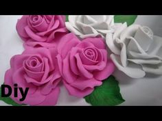 three white and pink roses with green leaves on a white tablecloth that says diy