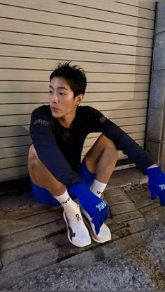 a young man sitting on the ground wearing blue and white socks with his legs crossed