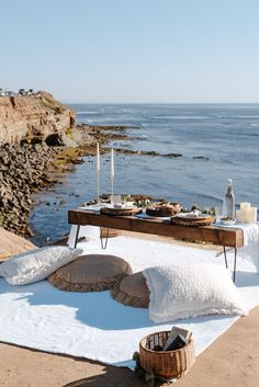 a picnic table set up on the beach with food and drinks in front of it