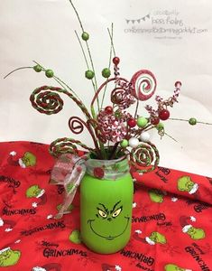 a green vase filled with candy canes and flowers on a red tablecloth covered table