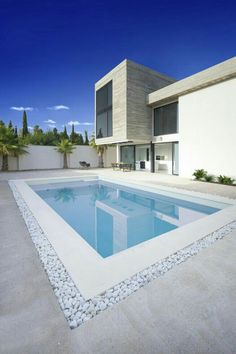 an empty swimming pool in front of a modern house