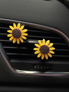 two yellow sunflowers are placed on the air vent in a car's dashboard