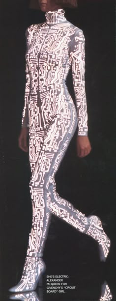 a woman in white and black patterned bodysuit walking down the runway with her legs spread out