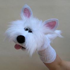 a white dog with its tongue out and eyes wide open, wearing a knitted sweater