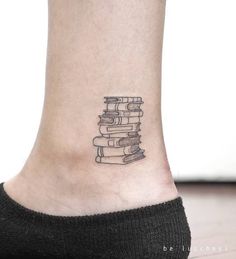 a small tattoo on the ankle of a woman's foot with books stacked up