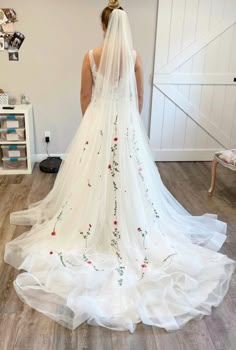 the back of a bride's wedding dress with flowers on it, and veil