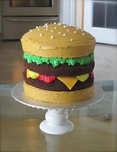 a hamburger cake sitting on top of a glass table