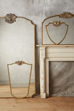 two mirrors sitting next to each other on top of a wooden floor near a fireplace