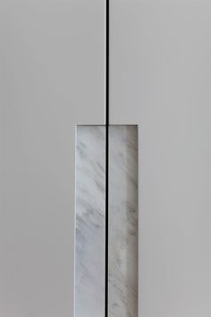 a tall white and black vase sitting on top of a floor next to a wall