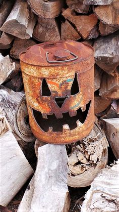 an old rusty can with a jack - o'- lantern face on it sitting in front of firewood