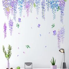 purple and blue flowers are hanging from the ceiling in front of a wall with butterflies on it