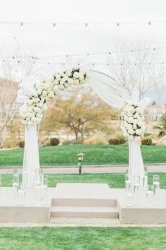 an outdoor ceremony setup with white flowers and candles