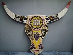 a bull's head with colorful designs on it is hanging from the wall in a room