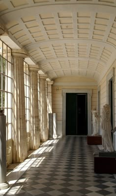 the sun shines through the windows onto an ornate hallway with statues on either side