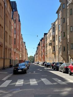 cars are parked on the side of an empty street in front of apartment buildings,