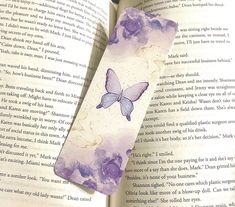 a bookmark with a butterfly on it sitting in front of an open page of a book