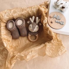 two knitted animals are sitting in a box next to cotton balls and a sign that says hello world