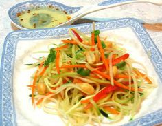 a white plate topped with noodles and veggies next to a bowl of sauce