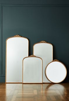 three mirrors sitting next to each other on top of a hard wood floor in front of a green wall