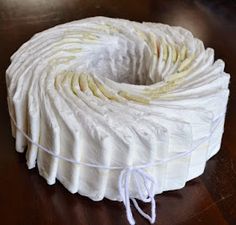 a roll of white yarn sitting on top of a wooden table next to a pair of scissors