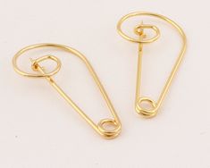 two pairs of gold colored metal clips on a white surface, one has a hook and the other has a loop