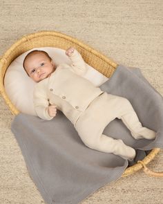 a baby laying in a basket on the floor