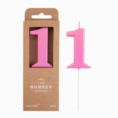 a pink candle in a cardboard box with the number one on it's stick