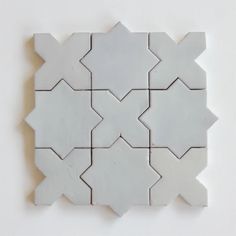 a white tile pattern on the wall with an interesting design in it's center