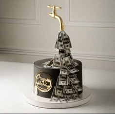 a cake decorated with money and a golden faucet sticking out of the top