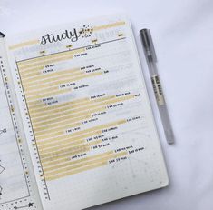 an open notebook with some writing on it and a pen next to it, sitting on a white surface