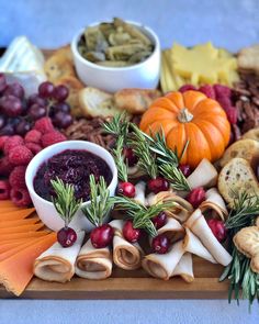 an assortment of cheeses, crackers and fruit on a wooden platter