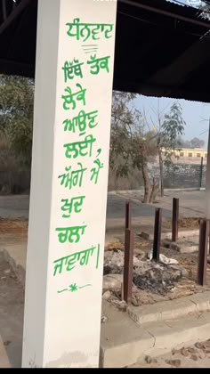 a white sign with green writing on it in front of a building under construction area