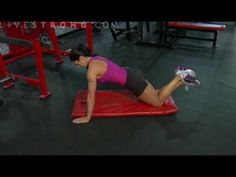 a woman doing an exercise on a mat in the gym with dumbbells and gloves