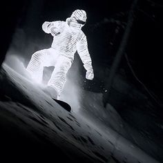 a man in white snowsuit standing on skis at night with light coming from behind him