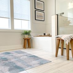 a white bathroom with two stools and a rug