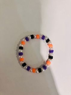 an orange, black and white beaded bracelet on a white background with space for text