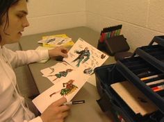 a woman sitting at a desk drawing on paper