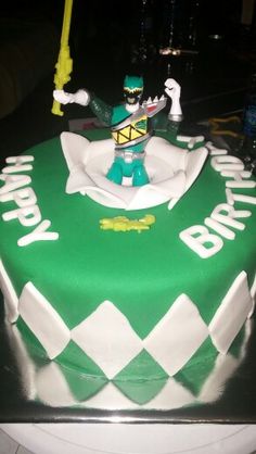 a green and white birthday cake with a toy figure on top