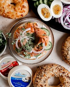 an assortment of food including bagels, salads and other items on a table