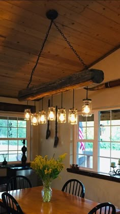 a dining room table and chairs with lights hanging from the ceiling