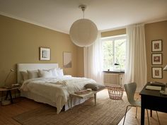 a bed sitting in a bedroom next to a table with a lamp on top of it