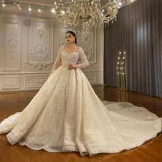 a woman in a white wedding dress standing next to a chandelier with lights on it