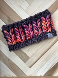 a close up of a knitted headband on a wooden floor with wood planks