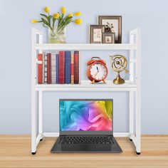 an open laptop computer sitting on top of a white book shelf next to a vase with yellow flowers