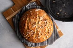 a loaf of bread sitting on top of a cutting board next to a skillet