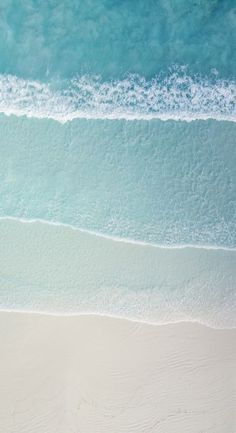 two people walking on the beach with surfboards